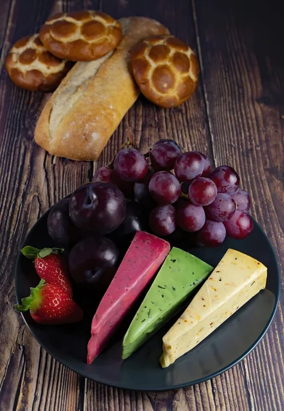 Dutch cheese types on plate and bread and fruit on wooden backdrop