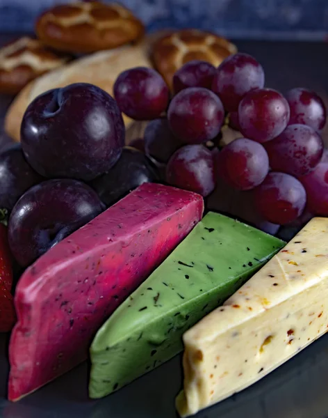 Dutch cheese types on plate and bread and fruit on wooden backdrop