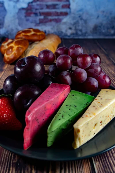 Dutch cheese types on plate and bread and fruit on wooden backdrop