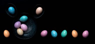 Üst manzara pastel renkli paskalya yumurtaları koyu granit bir tabakta siyah arka planda..