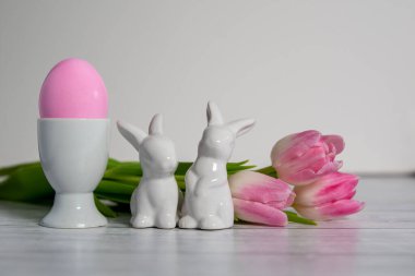 Pembe Paskalya yumurtası, porselen paskalya tavşanları ve aynı pastel renkli pembe beyaz laleli porselen yumurtalar. Beyaz bir arka planda. .