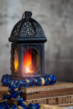 Ramazan feneri aydınlansın ve bir Arabesk kutusunun üzerinde eski moda veya çevresel bir mavi Arapça tespih bulunsun. .