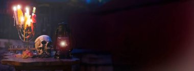 Erimiş mumlar eski masada ve kafatası karanlık Cadılar Bayramı sahnesinde