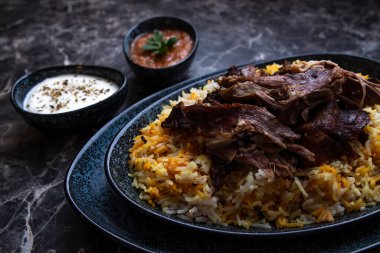 Kabsa pilavı ve ızgara kuzu ve iki küçük tabak yoğurt ve acı sos..