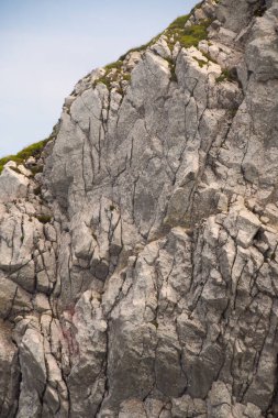 Dağın kenarında mavi bir gökyüzü ve çimenli bir arazi. Taş katmanlı..