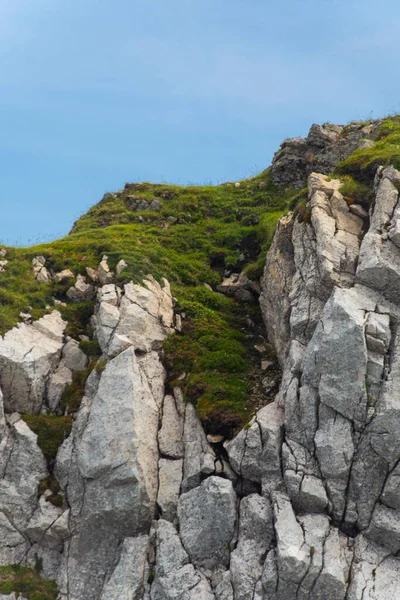 stock image A blue sky and grassy land on the edge of the mountain. with rocks.