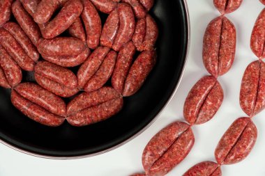 Çiğ ev yapımı sosisler yakın plan beyaz arka planda pişirme tavasında izole edilir.