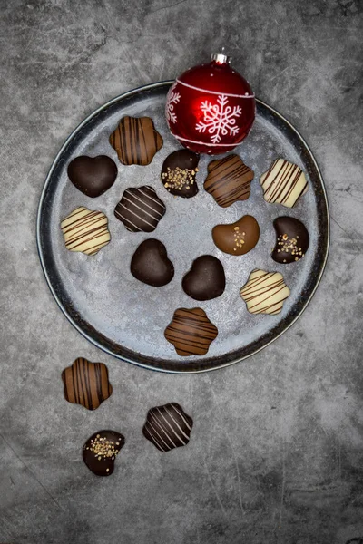 Christmas sweets, chocolate biscuits in plate and red Christmas tree ball gray table.