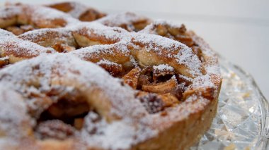 Evde yapılmış elmalı turta, arka planda kırmızı çiçekler.