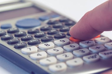 Hesap makinesi ve insan parmağı hesaplanıyor. Makro fotoğraf.