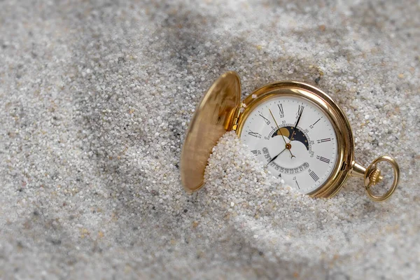 Pocket watches, vintage gold old watch in the sand in daylight.