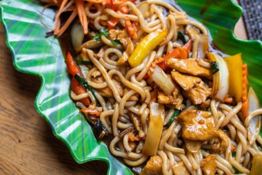 Soba, udon, yeşil tabakta tavuk ve sebzeli Asya buğday eriştesi.