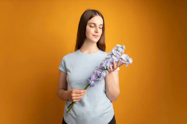 Young beautiful woman watching at beautiful bouquet of blue flowers in the hands. Delphinium Flowers. High quality photo