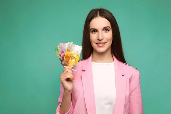 Elinde İsviçre banknotları tutan güzel genç bir kadın pozitif ve mutlu görünüyor ve kendine güvenen bir gülümsemeyle gülümsüyor. Yüksek kalite fotoğraf
