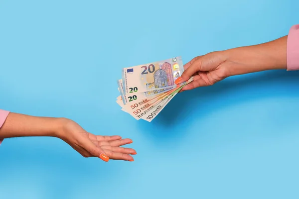 Hand giving euro currency and hand take, over blue background. Giving money to help. High quality photo