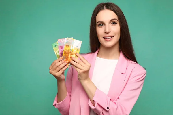 Beautiful young woman holding swedish krona banknotes looking positive and happy standing and smiling with a confident smile . High quality photo