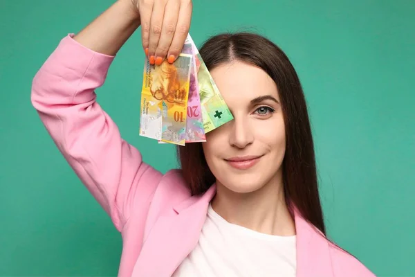 Beautiful young woman holding swedish krona banknotes near face, smiling happy with open mouth . High quality photo
