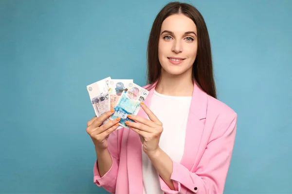 Birleşik Krallık banknotları tutan genç ve güzel bir kadın pozitif ve mutlu görünüyor ve kendine güvenen bir gülümsemeyle gülümsüyor. Yüksek kalite fotoğraf