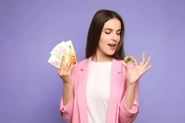 Bitcoin ve İsrail şekelleri tutan mutlu genç bir kadının portresi ve Bitcoin 'e bakmak. Yüksek kalite fotoğraf