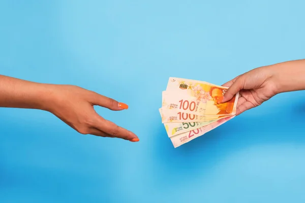 İsrail şekelleri ve el ele tutuşmalar, mavi arka planda. Yardım için para vermek. Yüksek kalite fotoğraf
