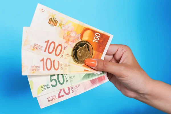 El ele tutuşan İsrail şekelleri para birimi ve mavi arka plan üzerinde dogecoin. Yüksek kalite fotoğraf