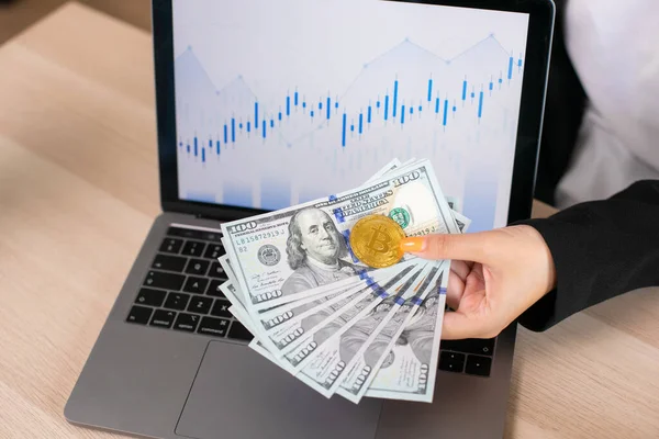 Dollar Biljetten Bitcoin Handen Houden Een Achtergrond Laptop Met Grafieken — Stockfoto