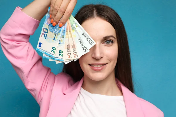 Avro banknotlarını yüzüne yakın tutan genç bir kadın. Yüksek kalite fotoğraf