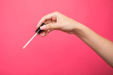 Woman hands holding concealer applicator isolated on pink background. High quality photo