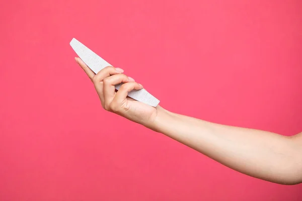 manicure and pedicure nail file in a hand isolated on pink background. cosmetic tool. High quality photo