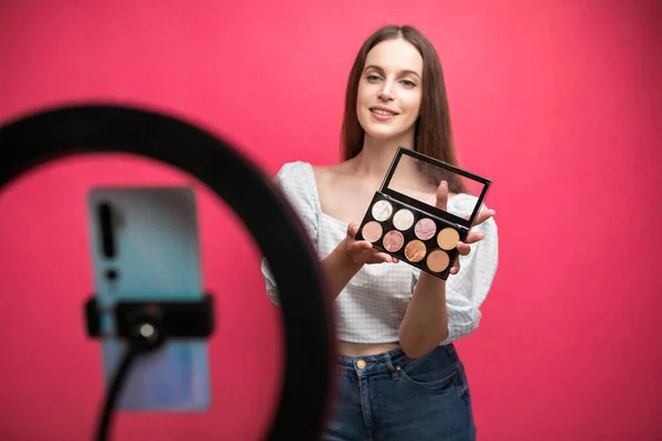 Güzellik blogcusu pembe arka planda makyaj dersi kaydediyor. Yüksek kalite fotoğraf