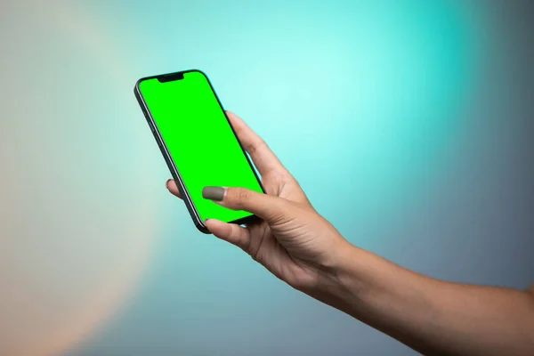 Woman hand Holding a Green Screen Smartphone scroll and touch display on colorful background. High quality photo