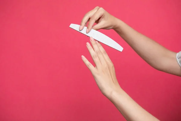 Woman hands manicure with nail file isolated on pink background. High quality photo