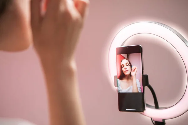 Beauty blogger recording makeup tutorial on phone camera. High quality photo