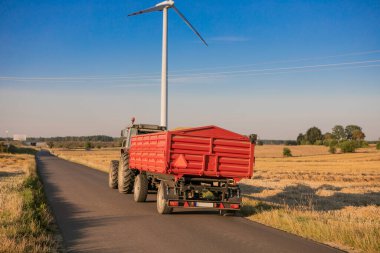 Aerial view of grain carrier on dirt road between agricultural wheat fields. Transportation of grain after being harvested by combine harvester during harvesting season. High quality photo