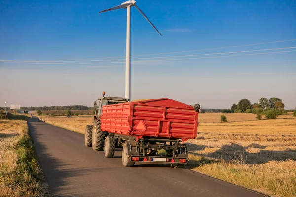 Aerial view of grain carrier on dirt road between agricultural wheat fields. Transportation of grain after being harvested by combine harvester during harvesting season. High quality photo