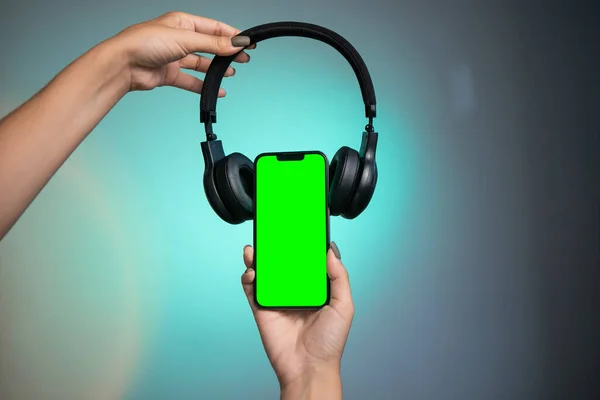 Modern headphone and gadget with green screen. Black headphones on phone. High quality photo