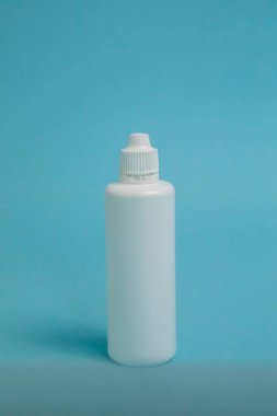 A bottle of liquid for lenses on a blue background. Mock up of liquid for lenses. High quality photo