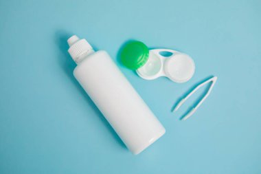 Packages with contact lenses, case, tweezers and drops on blue background. High quality photo