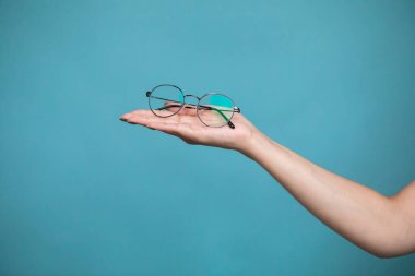 Female hand with stylish glasses on colorful background. High quality photo