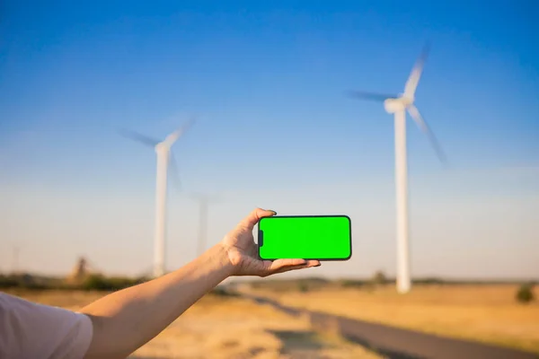 Green screen smartphone on the windmills background. Chroma key. windmills green energy. High quality photo