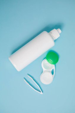 Packages with contact lenses, case, tweezers and drops on blue background. High quality photo