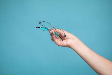 Female hand with stylish glasses on colorful background. High quality photo