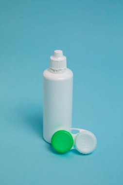 Packages with contact lenses, case and drops on blue background. High quality photo