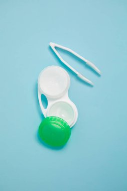 Case with contact lenses and tweezers on light blue background. High quality photo