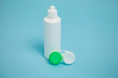 Packages with contact lenses, case and drops on blue background. High quality photo