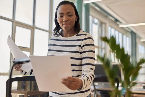 明るい現代的なオフィスで彼女の机に立っている間 書類を読んでいる若いアフリカのビジネスマンの女性に焦点を当て — ストック写真