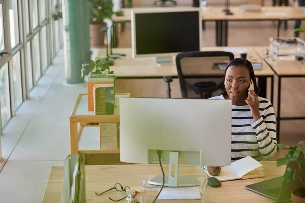 아프리카 사업가가 현대식 사무실에서 책상에 앉아서 통화를 하면서 필기를 — 스톡 사진