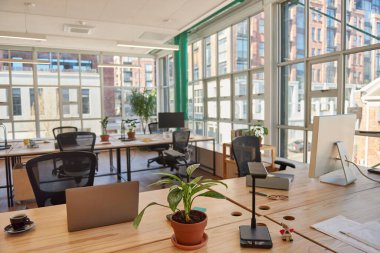 Çalışma saatlerinden sonra masa ve sandalyelerin, bilgisayarların ve ofis malzemelerinin bulunduğu modern bir ofis.