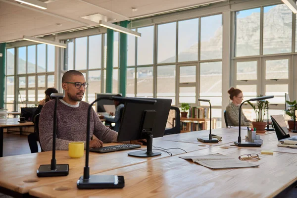 年轻的商人和同事们一起在一个宽敞的开放式办公空间的桌子前的电脑上工作 — 图库照片