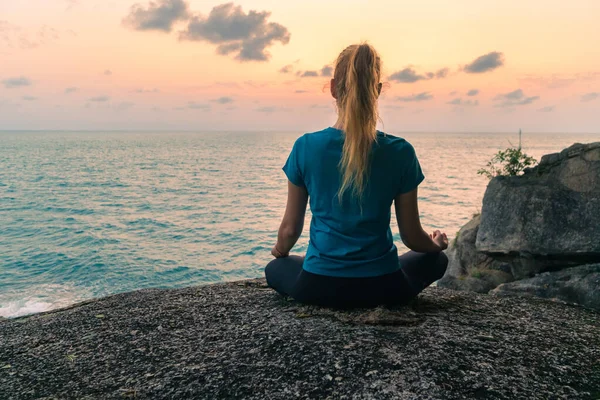 Egy Fiatal Lótuszpozícióban Meditál Sziklákon Napkeltekor Színes Háttérben — Stock Fotó